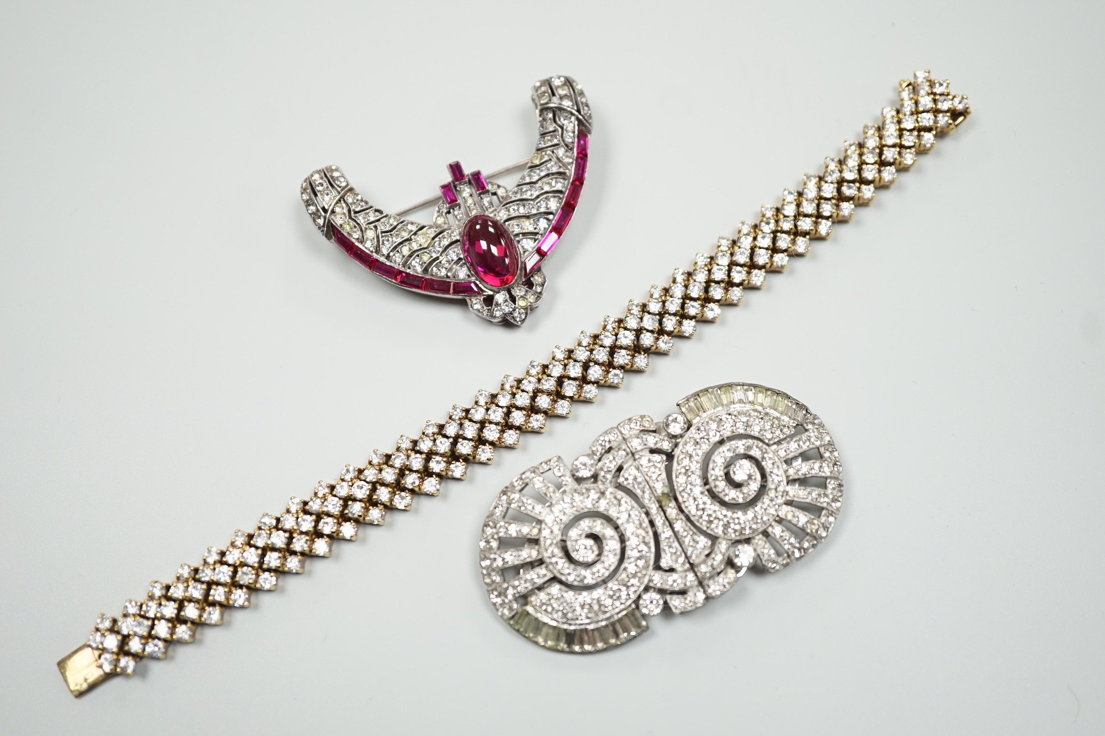 An Art Deco style white metal and two colour paste set curved clip brooch, width 56mm, a paste set double clip brooch, width 65mm and and a similar paste set gilt 925 bracelet, 18.5cm.